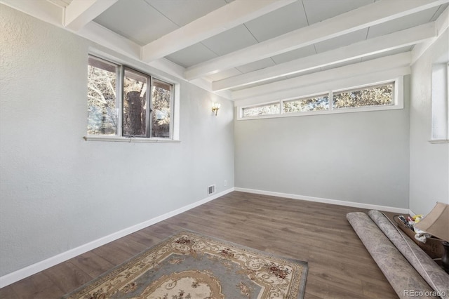 unfurnished room with dark wood-type flooring and beam ceiling