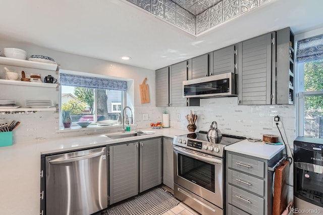6311 Xavier St, Arvada, CO 80003 - kitchen featuring gray cabinets, stainless steel appliances, a sink, light countertops, and decorative backsplash