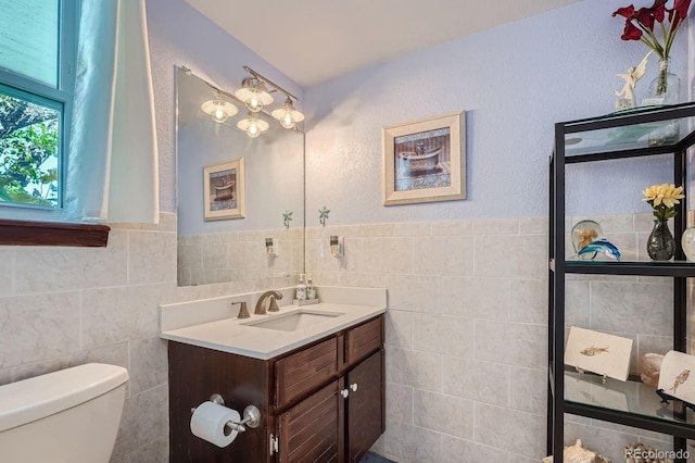 6311 Xavier St, Arvada, CO 80003 - half bathroom featuring vanity, tile walls, toilet, and wainscoting