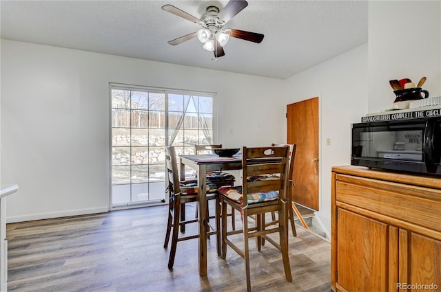 dining area with wood-type flooring and ceiling fan