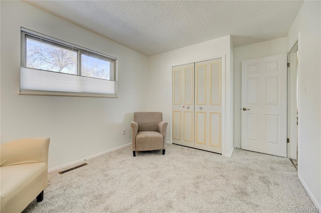 sitting room featuring a textured ceiling and light carpet