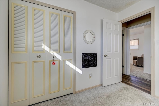 foyer entrance with light colored carpet and a textured ceiling