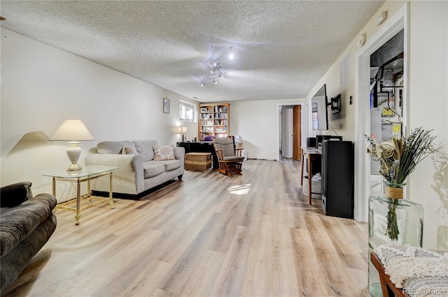 living room with a textured ceiling, light wood-type flooring, and track lighting