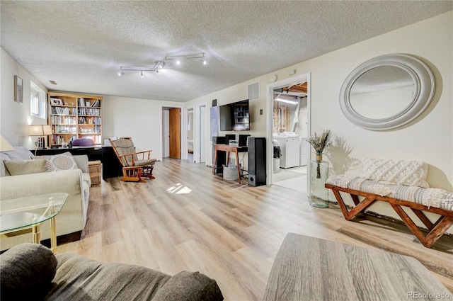 living room with separate washer and dryer, a textured ceiling, and light wood-type flooring