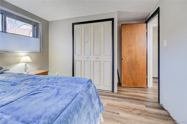 bedroom featuring light wood-type flooring, a textured ceiling, and a closet