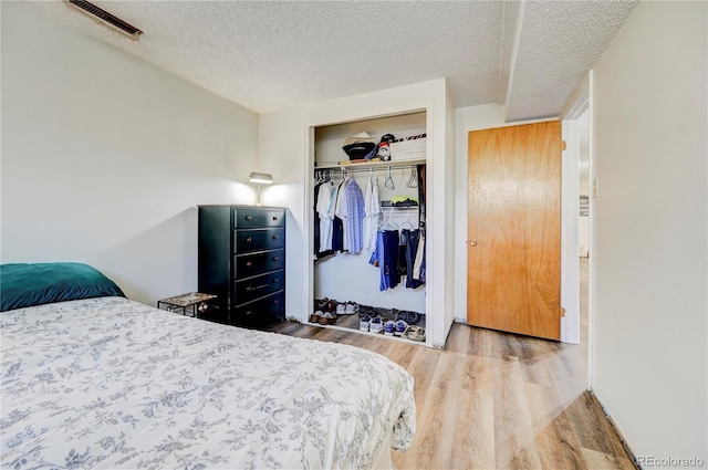 bedroom featuring wood-type flooring, a textured ceiling, and a closet