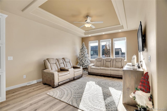 living room featuring ceiling fan, light hardwood / wood-style floors, and a raised ceiling