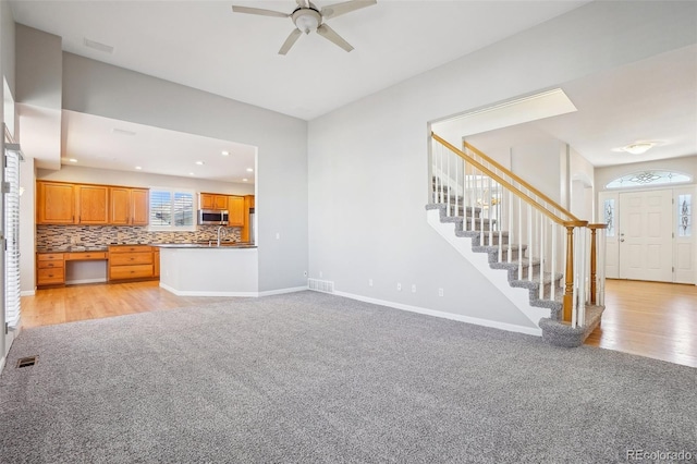 17309 Witten Ct, Parker, CO 80134 - unfurnished living room featuring baseboards, light carpet, stairway, a ceiling fan, and visible vents