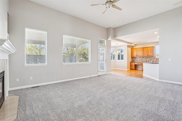 17309 Witten Ct, Parker, CO 80134 - unfurnished living room with light carpet, a fireplace with flush hearth, ceiling fan with notable chandelier, and baseboards