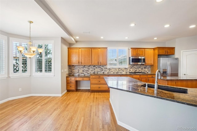 17309 Witten Ct, Parker, CO 80134 - kitchen with an inviting chandelier, brown cabinetry, a sink, stainless steel appliances, and decorative backsplash