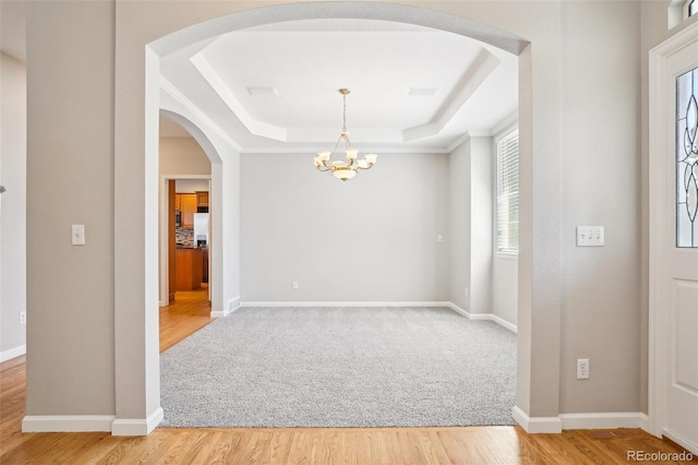 17309 Witten Ct, Parker, CO 80134 - foyer entrance featuring light wood-type flooring, baseboards, a chandelier, a raised ceiling, and arched walkways