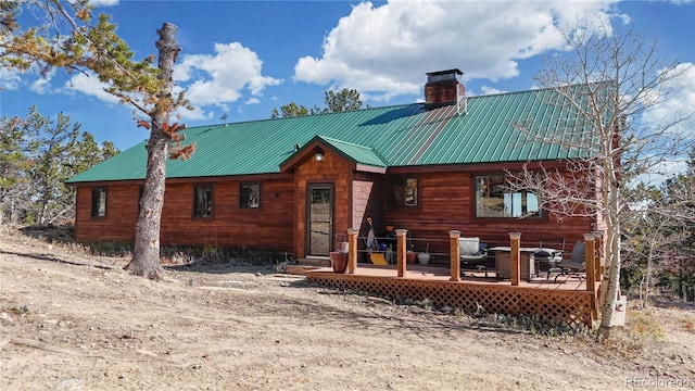 view of front of home featuring a deck, metal roof, and a chimney