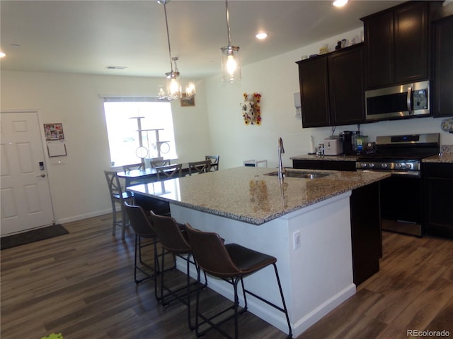 kitchen featuring sink, stainless steel appliances, dark hardwood / wood-style flooring, pendant lighting, and a center island with sink