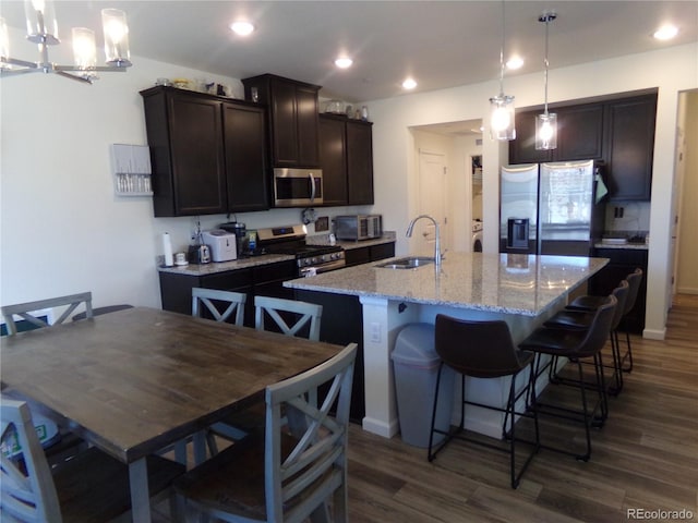 kitchen with appliances with stainless steel finishes, a center island with sink, dark wood-type flooring, and sink