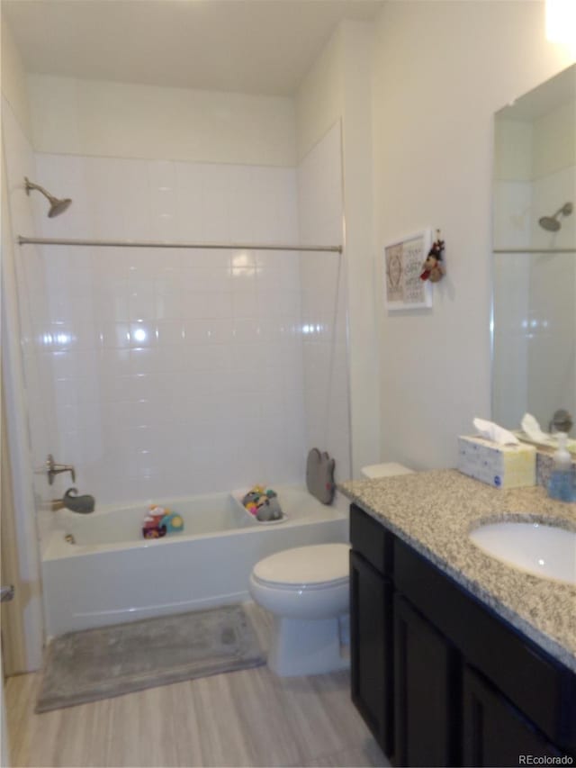 full bathroom with hardwood / wood-style floors, vanity, tiled shower / bath combo, and toilet