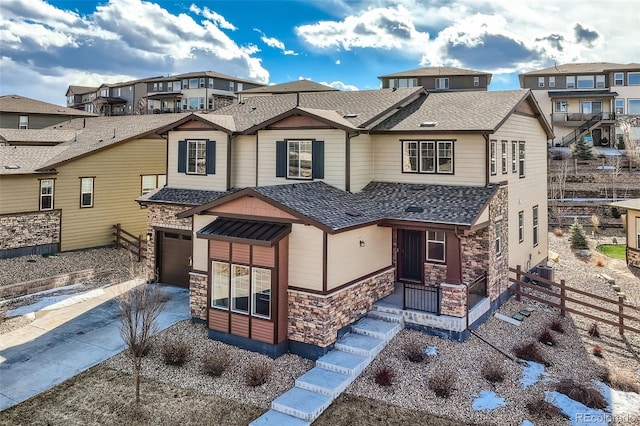 view of front of house with an attached garage, stone siding, driveway, roof with shingles, and a residential view