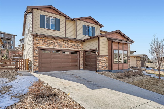 view of front of home with a garage, stone siding, fence, and driveway