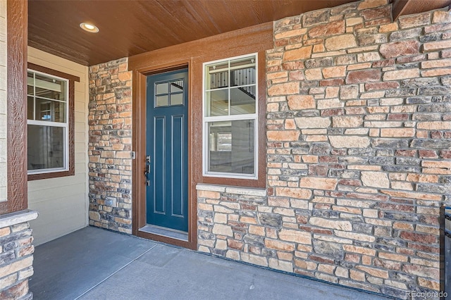 view of exterior entry featuring a porch and brick siding