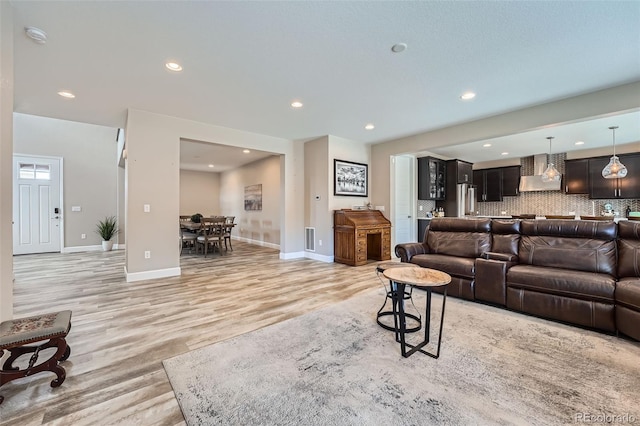 living room featuring light wood-style flooring, visible vents, baseboards, and recessed lighting