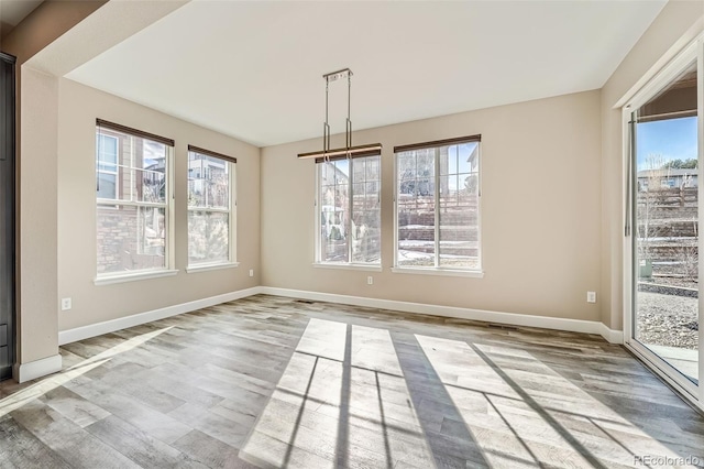 unfurnished dining area with light wood-type flooring and baseboards