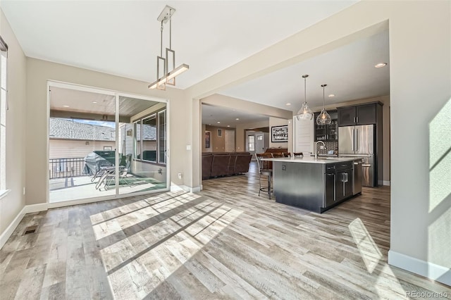 kitchen featuring high end refrigerator, light countertops, light wood-style floors, open floor plan, and a kitchen bar