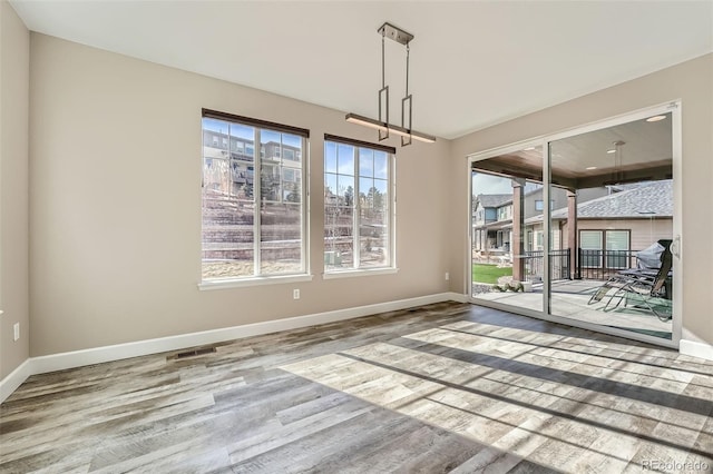 unfurnished dining area featuring wood finished floors, visible vents, and baseboards