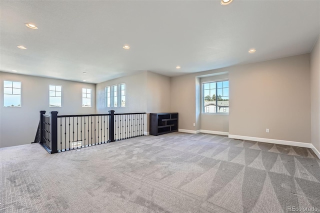 carpeted spare room featuring a wealth of natural light, baseboards, and recessed lighting