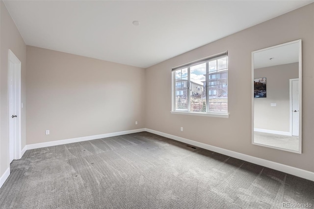 empty room featuring carpet floors, visible vents, and baseboards