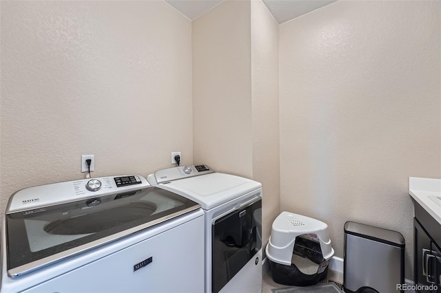 laundry area with washer and dryer, cabinet space, and a textured wall