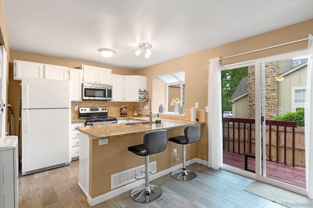18131 E Arizona Ave Unit B, Aurora, CO 80017 - kitchen with stainless steel appliances, a peninsula, light wood-style flooring, and decorative backsplash