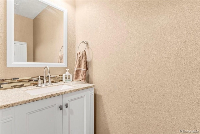 18131 E Arizona Ave Unit B, Aurora, CO 80017 - bathroom with vanity, decorative backsplash, and a textured wall