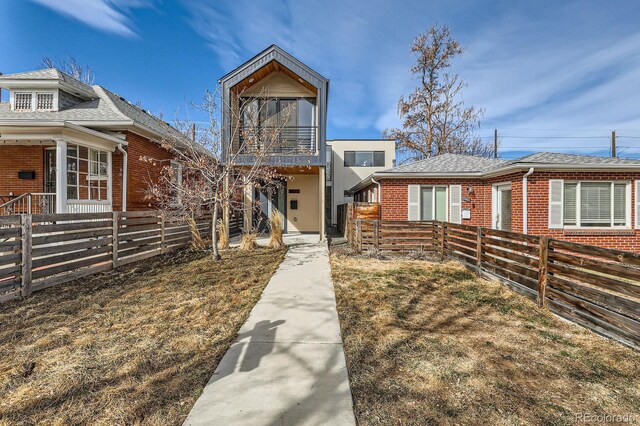 view of front of property with a balcony, fence private yard, and brick siding