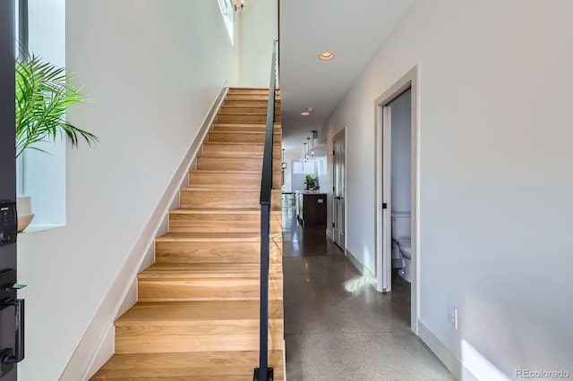 staircase with recessed lighting, baseboards, and finished concrete floors