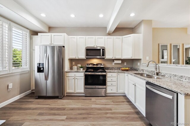 2945 W Riverwalk Cir Unit B, Littleton, CO 80123 - kitchen with appliances with stainless steel finishes, a sink, white cabinets, light stone counters, and a peninsula