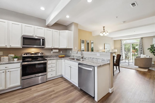 2945 W Riverwalk Cir Unit B, Littleton, CO 80123 - kitchen with appliances with stainless steel finishes, a sink, a peninsula, light wood-style floors, and beam ceiling