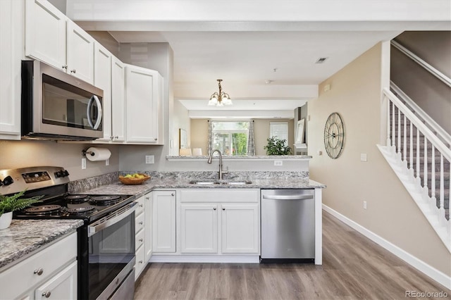 2945 W Riverwalk Cir Unit B, Littleton, CO 80123 - kitchen with stainless steel appliances, a sink, a peninsula, light wood finished floors, and baseboards