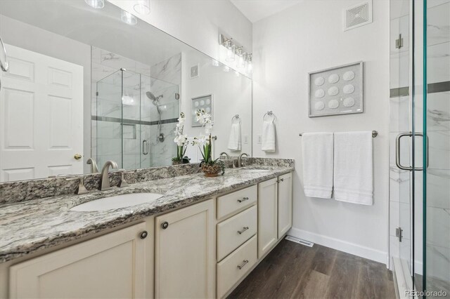 2945 W Riverwalk Cir Unit B, Littleton, CO 80123 - full bath featuring double vanity, wood finished floors, a marble finish shower, and baseboards