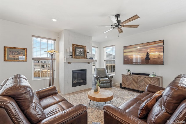 living area featuring ceiling fan, wood finished floors, a wealth of natural light, and a tile fireplace