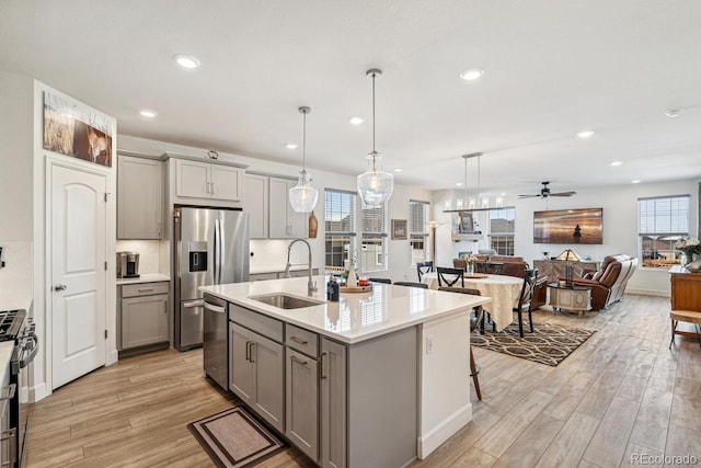 kitchen with a sink, light wood-type flooring, gray cabinetry, and appliances with stainless steel finishes