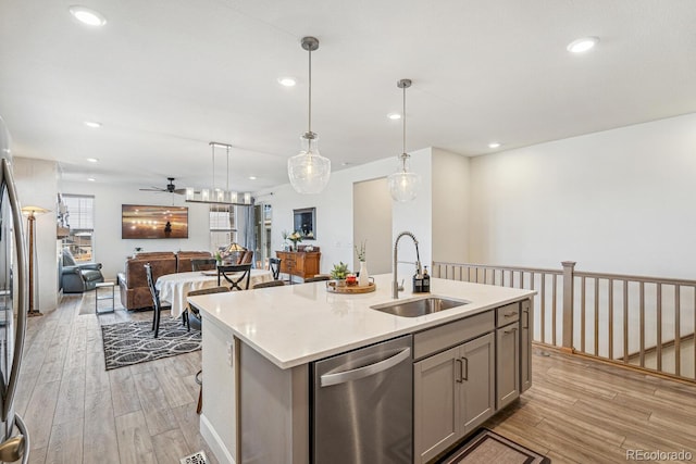 kitchen featuring light wood finished floors, gray cabinetry, appliances with stainless steel finishes, and a sink