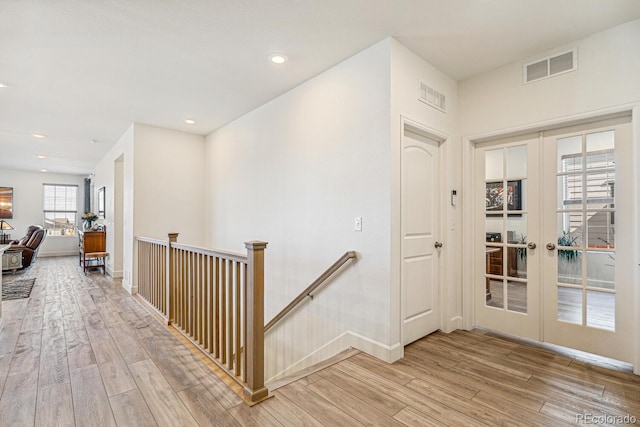 hall featuring an upstairs landing, french doors, visible vents, and light wood finished floors