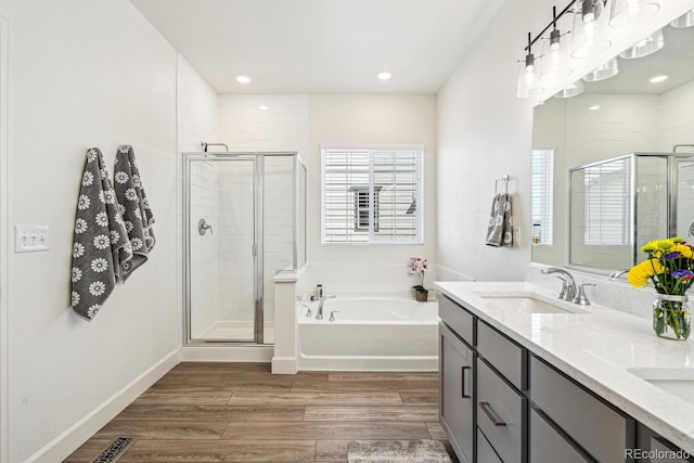 full bath featuring a sink, a garden tub, a stall shower, and wood finished floors