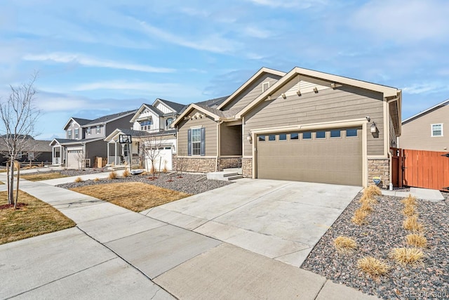 view of front facade with stone siding, fence, a residential view, concrete driveway, and an attached garage