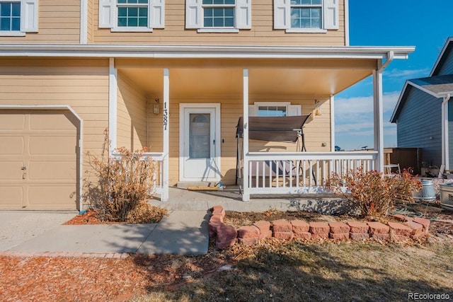 view of exterior entry with a garage and a porch