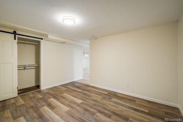 740 Lotus Way, Broomfield, CO 80020 - unfurnished bedroom with wood finished floors, baseboards, a closet, and a barn door