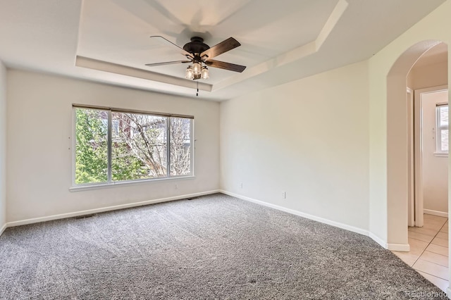 7838 W Layton Way, Littleton, CO 80123 - empty room featuring a tray ceiling, arched walkways, a ceiling fan, light carpet, and baseboards