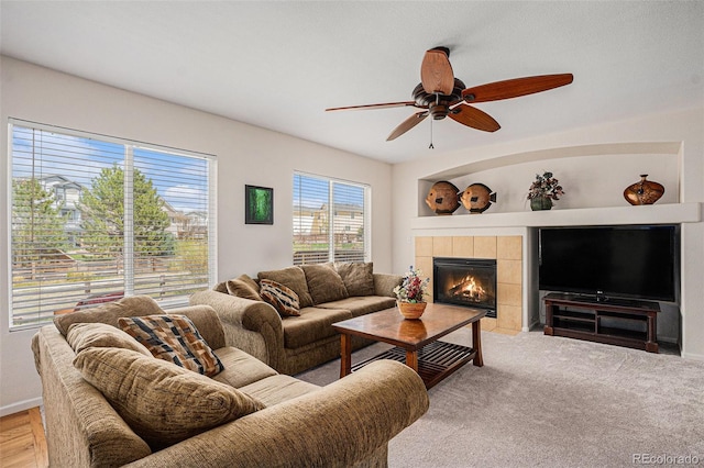 living area featuring baseboards, ceiling fan, and a fireplace