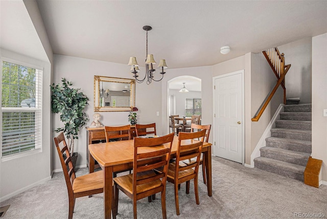 dining area featuring stairs, arched walkways, light colored carpet, and a wealth of natural light