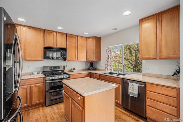 kitchen with appliances with stainless steel finishes, a sink, light countertops, light wood-style flooring, and recessed lighting