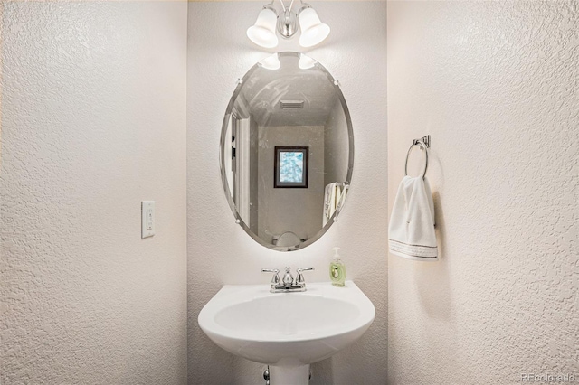 bathroom featuring visible vents, a sink, and a textured wall